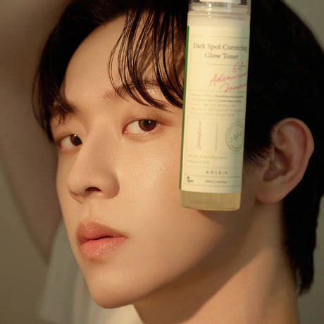 A model holding a bottle of the Axis-Y Dark Spot Correcting Glow Toner.